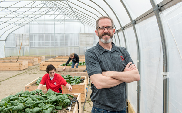 Kip Curtis and two students in a greenhouse