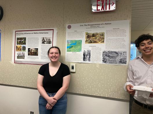 two students standing in front of posters